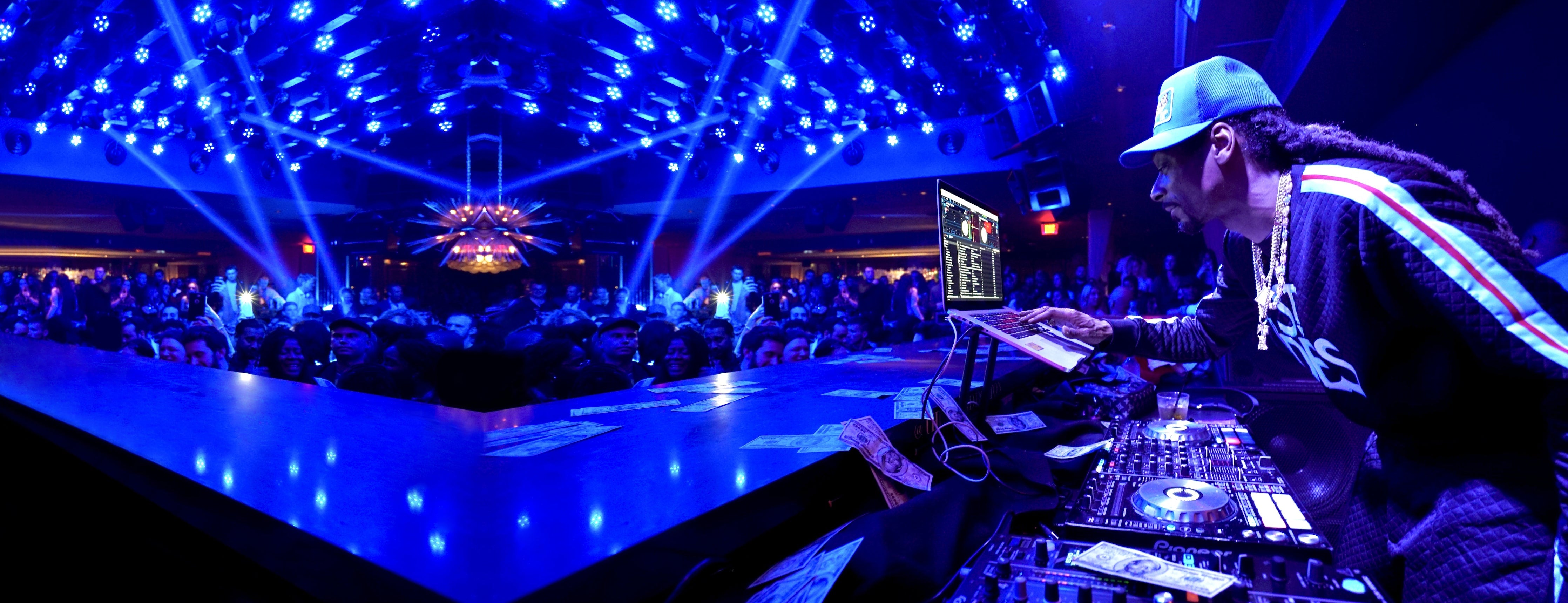 Snoop Dogg in front of a DJ set performing at a club