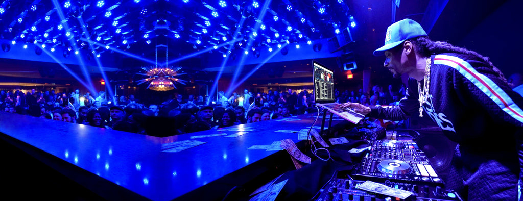 Snoop Dogg in front of a DJ set performing at a club